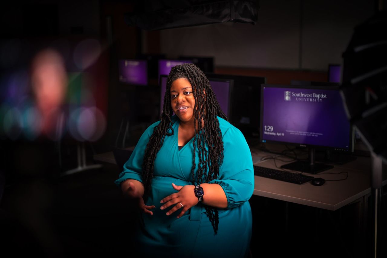 A faculty member standing in a university computer lab, mid-conversation.
